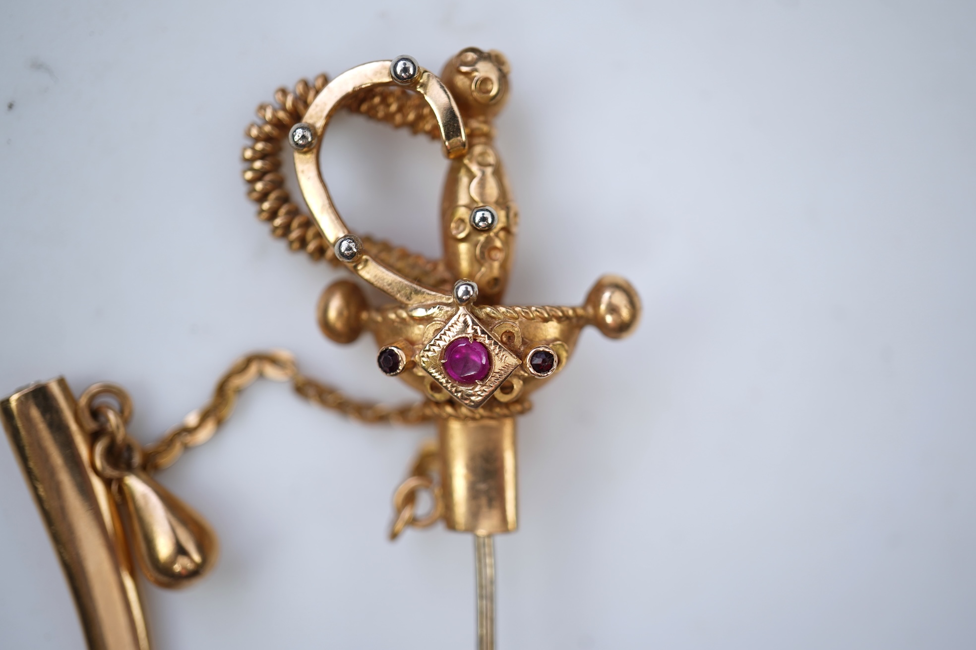 A gold and synthetic ruby jabot pin